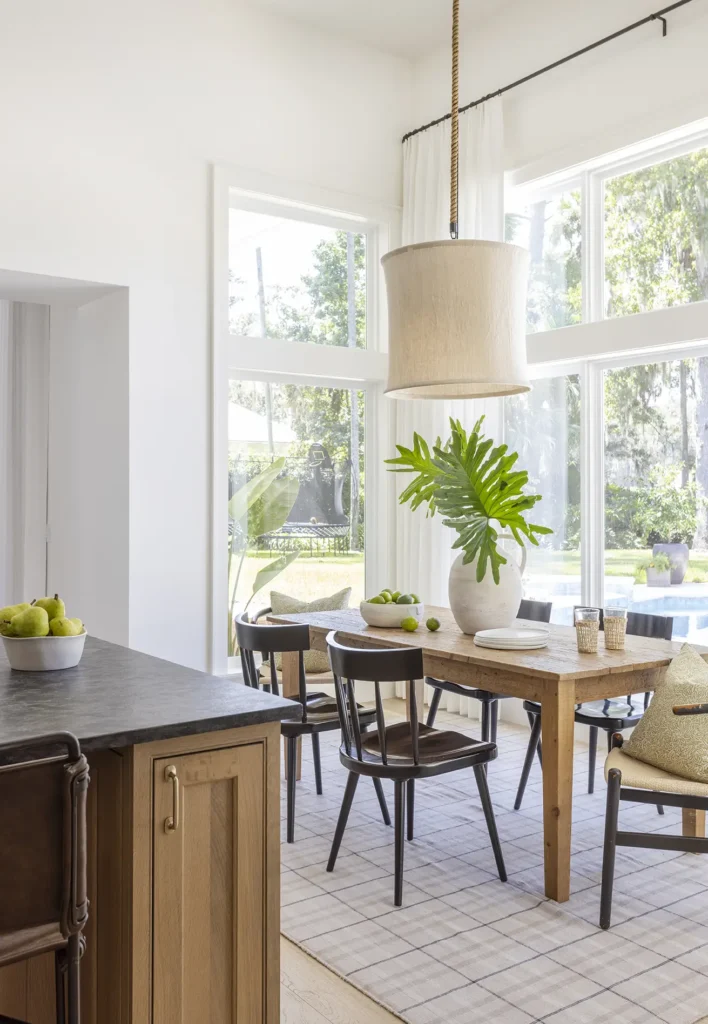 Custom dining room with large windows, natural wood table, and views of the pool in a Ponte Vedra custom home design by Alesch Luxury Custom Builders