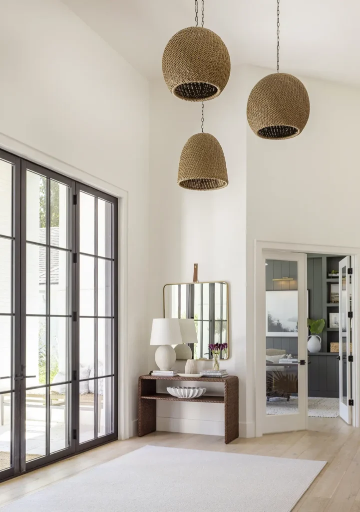Bright entryway design in custom home design Ponte Vedra renovation with woven pendant lights and natural wood console by Alesch Luxury Custom Builders.