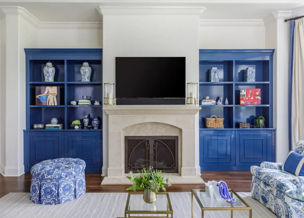 Custom-built living room with vibrant blue built-in cabinetry, limestone fireplace, and chinoiserie-inspired coastal décor in a Ponte Vedra Beach renovation.