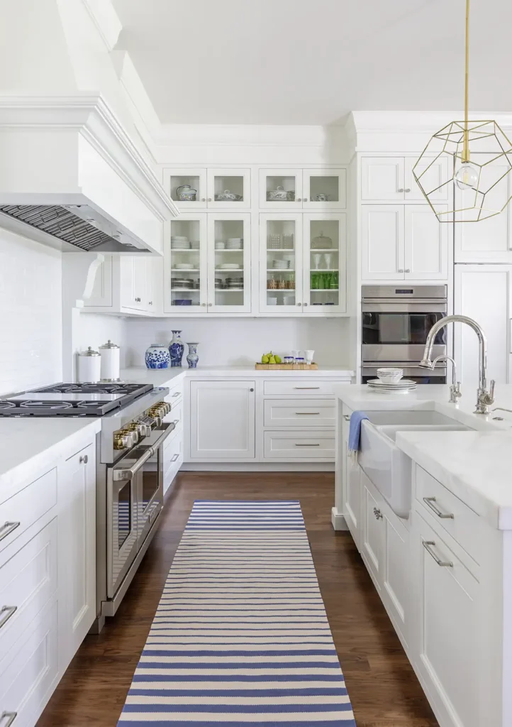 Bright white kitchen renovation with glass-front cabinets and striped runner in Ponte Vedra Beach custom home. Kitchen renovation built by Alesch.