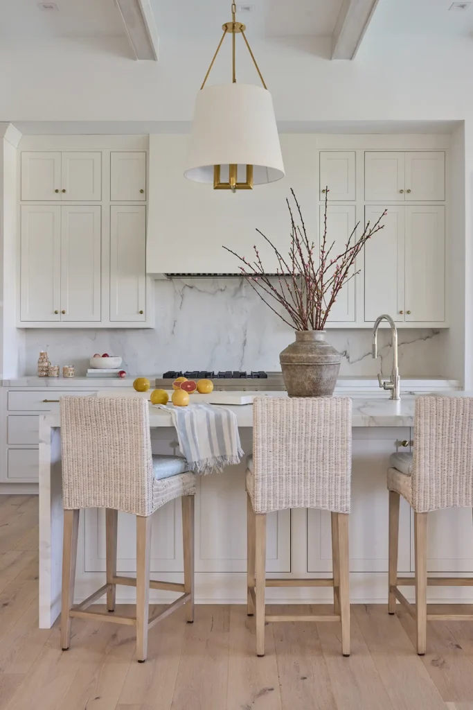 Ponte Vedra Beach Coastal Home Renovation Kitchen Renovation Details - Alesch Luxury Custom Builders Bright and modern kitchen renovation in a Ponte Vedra Beach coastal home, featuring woven barstools, a marble waterfall island, and custom white cabinetry.