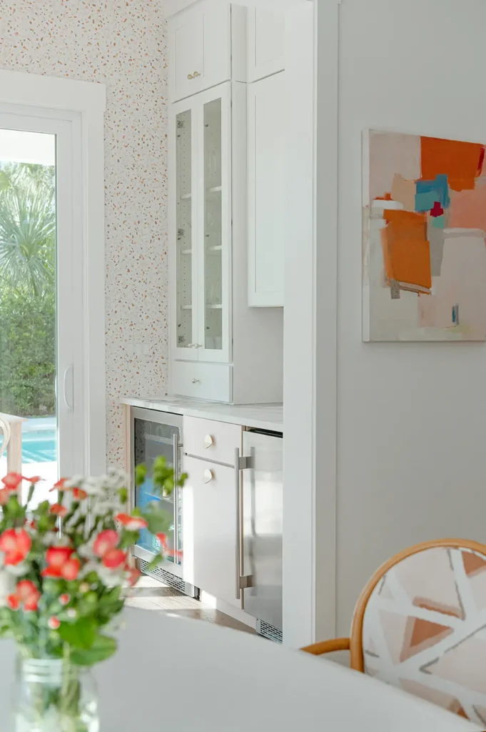 Ponte Vedra Home Renovation custom built-in beverage center with glass cabinet doors and marble countertop in a light-filled Ponte Vedra home renovation by Alesch Custom Builders
