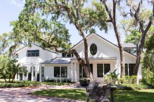 White board and batten custom home beneath live oaks, built by Alesch, custom home builder serving Jacksonville and the Northeast Florida coast
