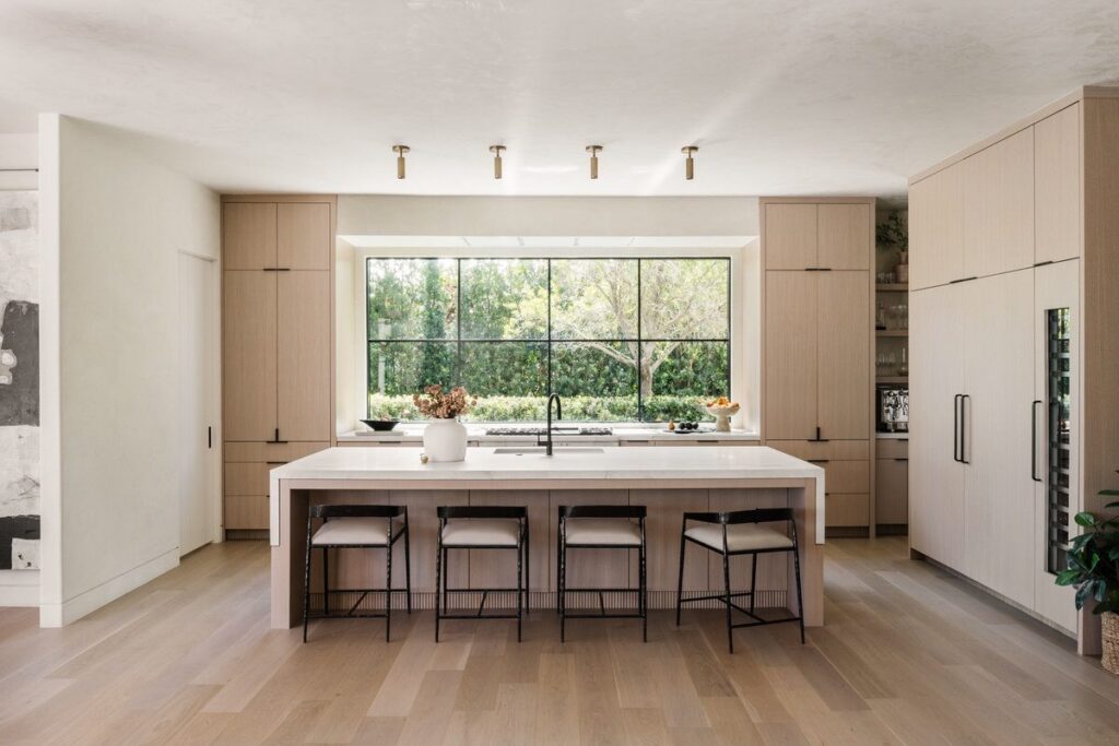 Light white oak kitchen with waterfall island and picture window, designed and built by Alesch, a design build firm serving Jacksonville