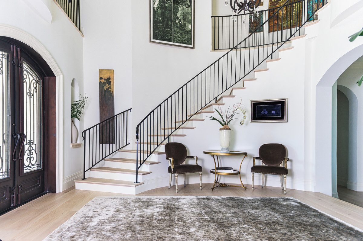 Renovated two-story foyer with curved staircase, wrought iron railing, and arched front doors by Alesch, home renovation builder in Ponte Vedra Beach
