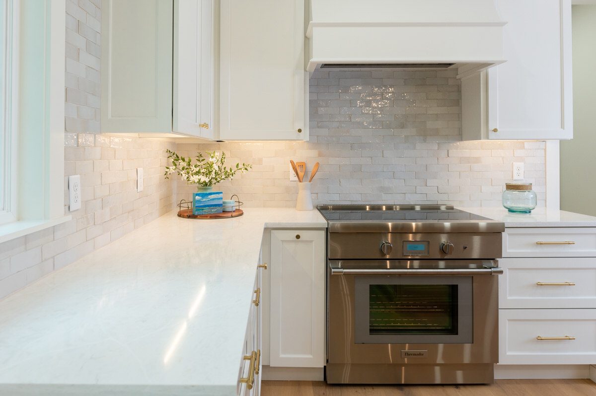 Renovated kitchen with white cabinetry, marble subway tile, and stainless range by Alesch, home renovation contractor near Ponte Vedra Beach